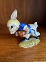 Front-side view of the Bunnykins Touchdown figurine showing bunny running with football and wearing helmet and blue jersey.