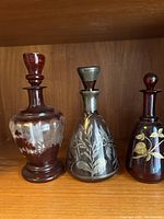 Three decorative glass decanters displayed side by side inside a wooden cabinet