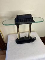 Front view of the desk lamp with glass top and chrome pillars on black base