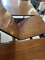 Close-up photo showing the jackknife style leaf extension mechanism of the wooden table.