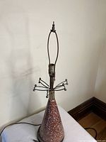 View of entire lamp showing the conical speckled ceramic base, metal ring decoration, and lamp socket area