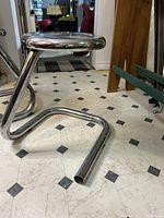 Photo of the paper clip style tubular metal frame of the stool, showing overall shape and chrome finish