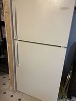 Closed view of white refrigerator with top freezer, showing front and handles.