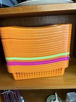 Stack of orange plastic organizing baskets with green and purple bands
