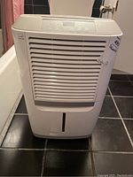 Front view of white Frigidaire dehumidifier showing air intake grill and water reservoir window.