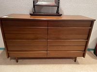 Front view of the six-drawer wood dresser on tapered legs against wall
