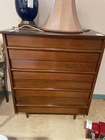 Front view of wood dresser showing six drawers with recessed handles and medium brown wood finish.