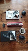 Top-down photo showing all items including DVD player, speakers, alarm clock, radio-player, blood pressure monitor, remotes, and cables.