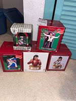 Five boxed Elvis Presley-themed Christmas ornaments arranged on carpet. Four Hallmark ornaments and one musical jukebox ornament.