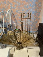 Wide view of collapsed fan fireplace screen with tool set stand behind