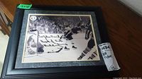 Framed black and white 13x15 hockey picture signed by Bobby Orr showing on-ice scene with crowd in background.
