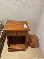 Front view of the Kroehler wood night stand and wicker basket showing overall condition and design.