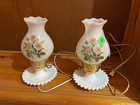 Pair of two white milk glass hurricane lamps with electric cords, floral rose design on glass shades, hobnail style base, 10 inches tall.