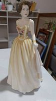 Full view of Royal Doulton porcelain figurine depicting a woman in a yellow floral dress, 9 inches tall.