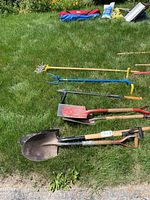 View of all garden tools laid on grass including shovels and rollers