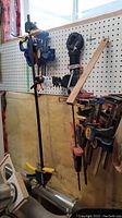 Wide view of various clamps hanging on pegboard including Quick-Grip and Craftsman clamps of different sizes