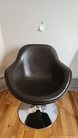 Front view of brown leather shell chair on chrome pedestal base