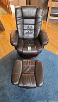 Front view of dark brown leather reclining chair and matching ottoman on wood base