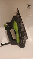 Side view of Rowenta iron showing black and green body with floral design on soleplate and model details.