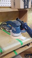 Photo of Bosch blue random orbital sander and Mastercraft angle grinder on shelf
