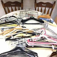 Image showing a collection of various types of hangers arranged on a table, including plastic, wood, metal wire, and padded hangers.