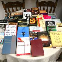Wide view of the assortment of used books spread over chairs and a surface showing titles and covers clearly.