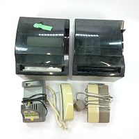 Two black Kimberly-Clark industrial paper towel dispensers with visible wear and dirt. Two vintage landline phones and a power adapter are in front of them.