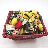 Basket filled with assorted new plush emoji keychains with original tags and clips visible.