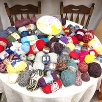 Wide view of yarn skeins on table in assorted colors and brands