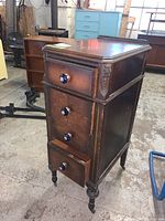 Front and side view of wooden 4-drawer dresser with blue pulls and casters, showing the carved corner details and turned legs.