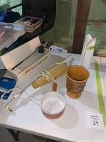 Photo showing the vintage electric turkey carver with box, wooden candle snuffer, and ceramic vase on white table.