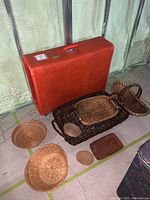 Orange large hard-sided luggage and assorted wicker baskets shown together on floor
