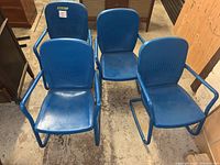 Four blue painted metal rocking chairs placed on concrete floor, showing overall appearance and arrangement.