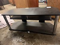 Front angle view of black TV stand showing top surface, two wooden compartments and metal legs