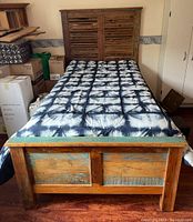 Overall view of single bed frame with mattress and tie-dye comforter