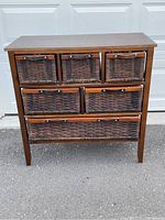 Front view of the wooden dresser with five wicker basket drawers.
