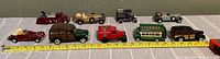 Full view of the nine diecast model cars lined up on a surface with a measuring tape showing sizes around 2 to 3 inches.