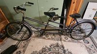 Full side view of purple tandem bicycle showing dual seats, frame and accessories