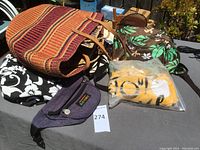 Woven tote bag with horizontal stripes, purple fannypack, and yellow folded t-shirt in plastic bag on table.