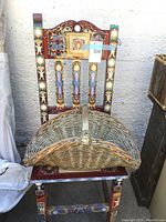 Hand painted wooden chair with intricate multicolor design and wicker basket placed on its seat.