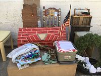 Wide view showing cardboard fireplace prop, Christmas wreath, gift bags, and holiday decorations arranged outdoors