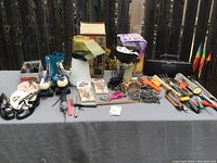 Wide shot of all assorted household items laid out on a gray surface including shoes, tools, pet grooming brush, popcorn popper, Sony radio, and Halloween decor.