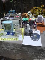 Full lot overview showing dinner set box, mugs, mini nightlight, placemats, and Cuisinart parts outside box