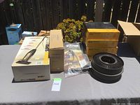 Lot displayed on table includes boxed Eureka Super Broom stick broom sweeper, Schoolmate cassette recorder, Seal Line dry bags, and Kodak carousel slide trays