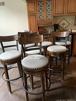 Group view of seven dark wood bar stools positioned in kitchen area