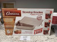 Front of the Camerons stovetop smoker box showing the smoker, wood chips, and recipe booklet included.