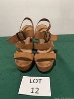 Front view of tan wedge sandals showing straps and buckle details.