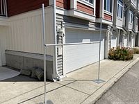 Full view of the adjustable backdrop stand set up on a sidewalk with the vertical poles and the horizontal crossbar attached.