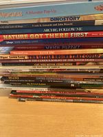 Stack of colorful children's books showing titles and authors, including pop-ups, storybooks, and animal-themed books.