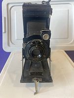 Front view of the Kodak Autographic No. 1A Pocket Series II folding camera showing the bellows, lens, viewfinder, and folding stand.